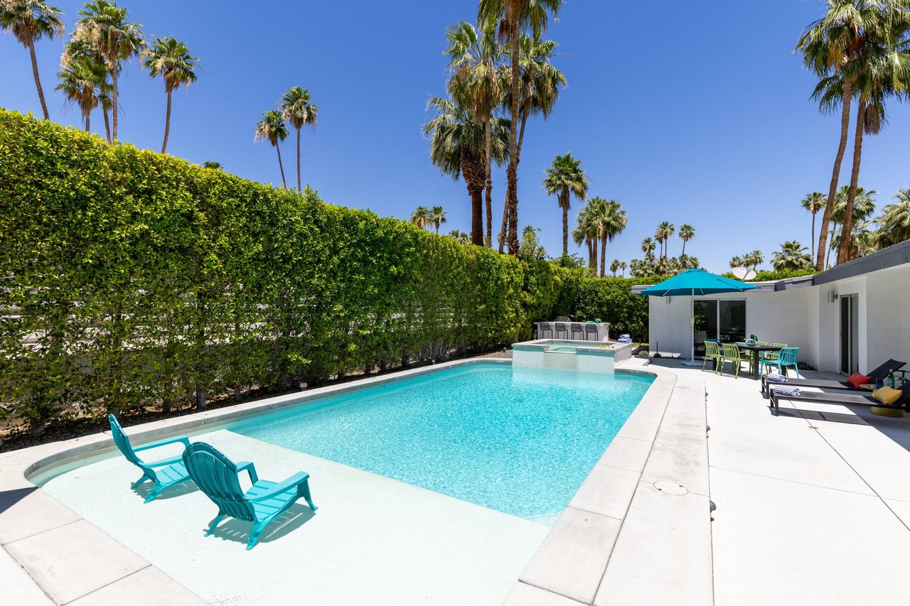 View of pool and spa looking toward the outdoor BBQ grill and corn hole area.