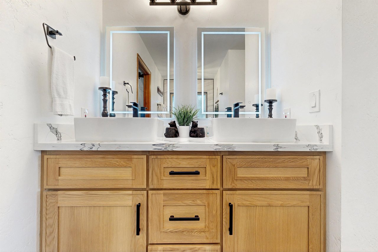 Ensuite bathroom with dual vanity sinks, modern fixtures, standalone tub, and walkin shower.