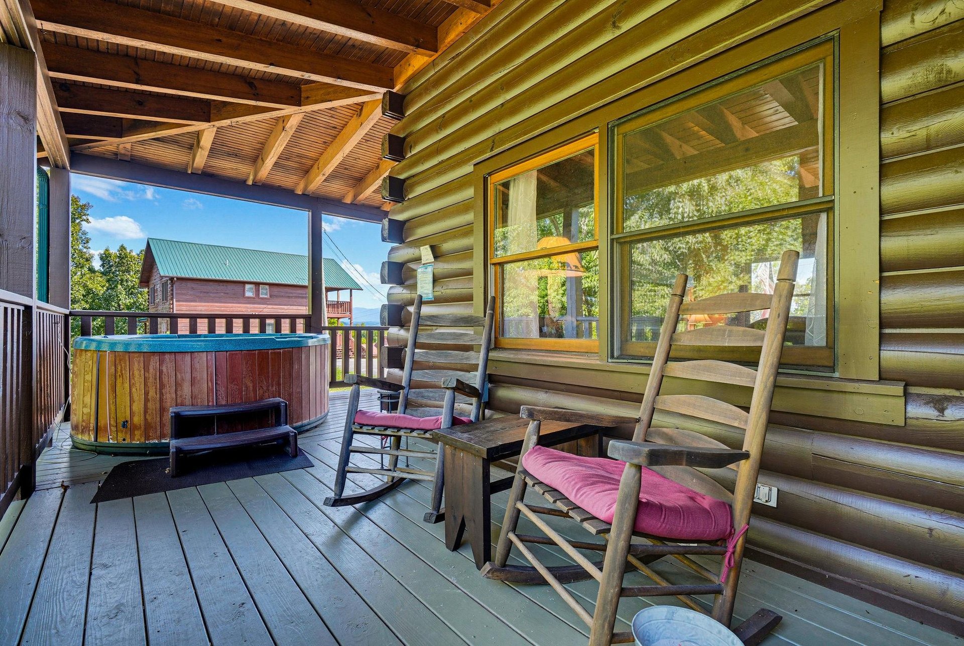 Unwind in your own private retreat with rustic rocking chairs and a bubbling hot tub, all tucked under a vaulted woodbeam porch. The cozy deck invites you to relax, breathe in the fresh mountain air,