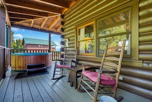 Unwind in your own private retreat with rustic rocking chairs and a bubbling hot tub, all tucked under a vaulted woodbeam porch. The cozy deck invites you to relax, breathe in the fresh mountain air,