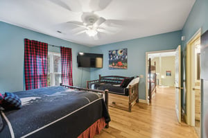 Unwind in this welcoming bedroom, where rustic log beds meet modern comfort. Natural light streams through plaid curtains, while a ceiling fan and flatscreen TV ensure your stay is cozy and convenien