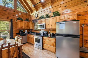 Step into your warm cabin kitchen with soaring wood ceilings, natural light streaming in, and everything you need to cook, gather, and feel right at home.
