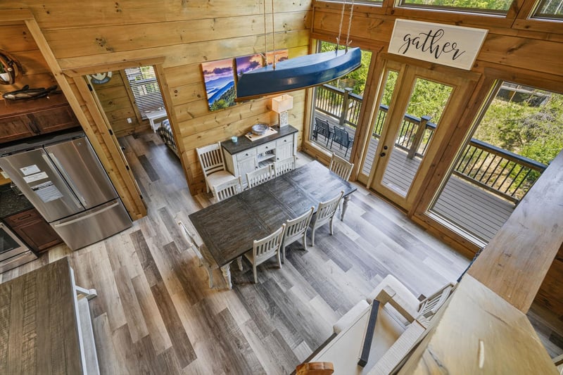 Step into your rustic cabin where warm wood beams frame soaring ceilings and windows flood the space with natural light.
