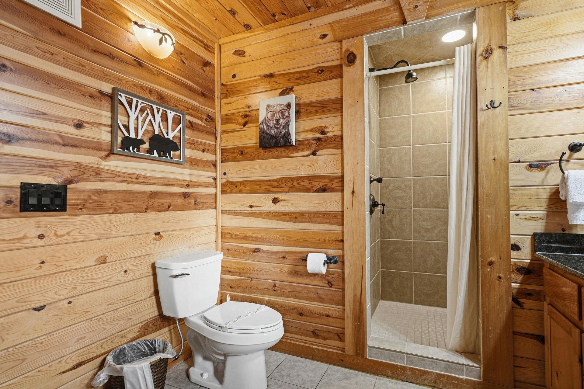 Enjoy your private rustic bathroom with natural wood walls, tiled shower, and charming cabin décor for a cozy mountain retreat experience.