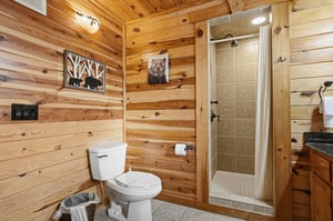 Enjoy your private rustic bathroom with natural wood walls, tiled shower, and charming cabin décor for a cozy mountain retreat experience.