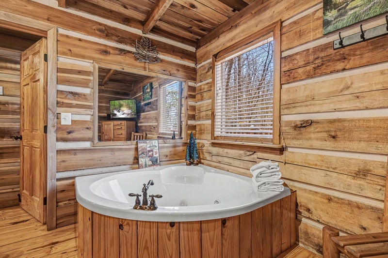 Unwind in your private rustic spa with soaking tub surrounded by warm cabin logs and forest views.