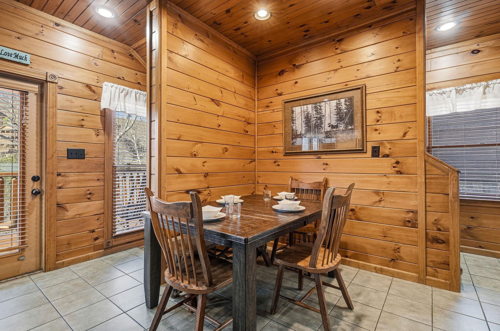 Gather around the rustic dining table where the warm glow of knotty pine walls creates a cozy mountain retreat atmosphere perfect for your morning coffee or evening meals together.