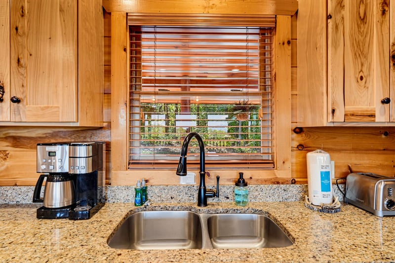 Your fully equipped kitchen features warm wood cabinetry, granite countertops, and a double sink with modern fixtures—everything you need to prepare meals in comfort during your stay.