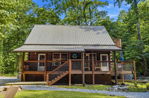 Rustic log cabin exterior nestled in a lush forest setting, offering a peaceful retreat surrounded by mature trees and natural beauty.