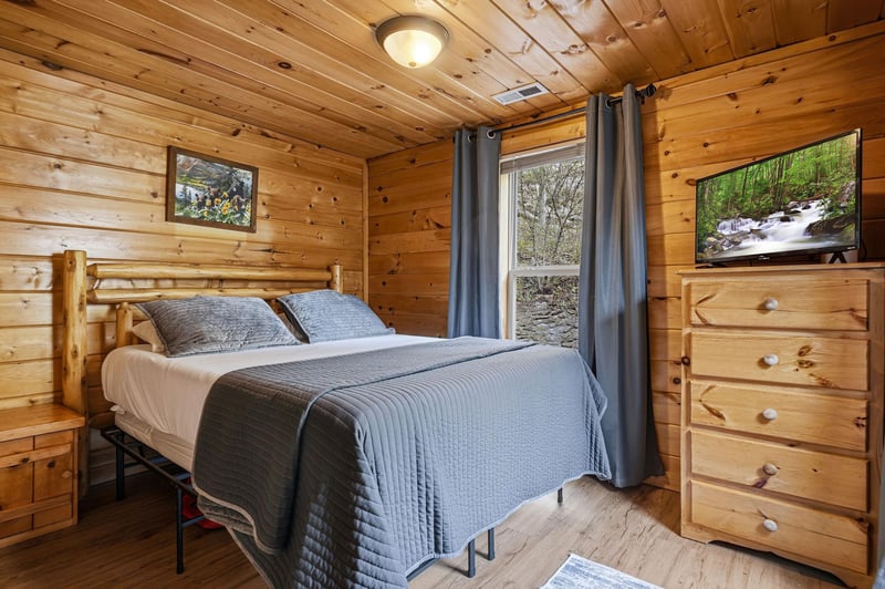 Drift off in this cozy log cabin bedroom, where warm wood walls and soft blue linens create your perfect mountain retreat sanctuary.