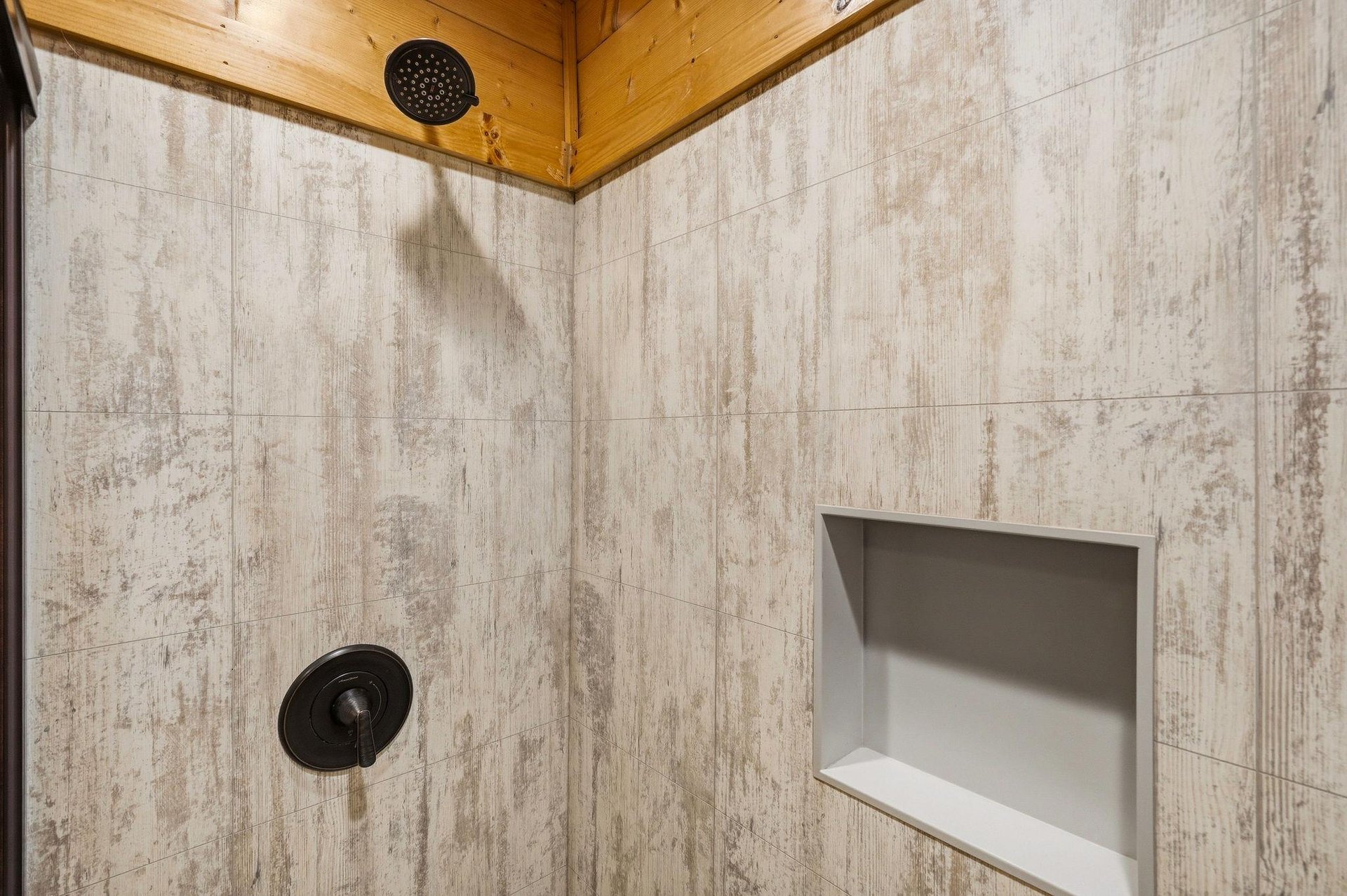 Relax under the warm glow of woodaccented ceilings in your modern, beautifully tiled shower with convenient builtin storage niche.