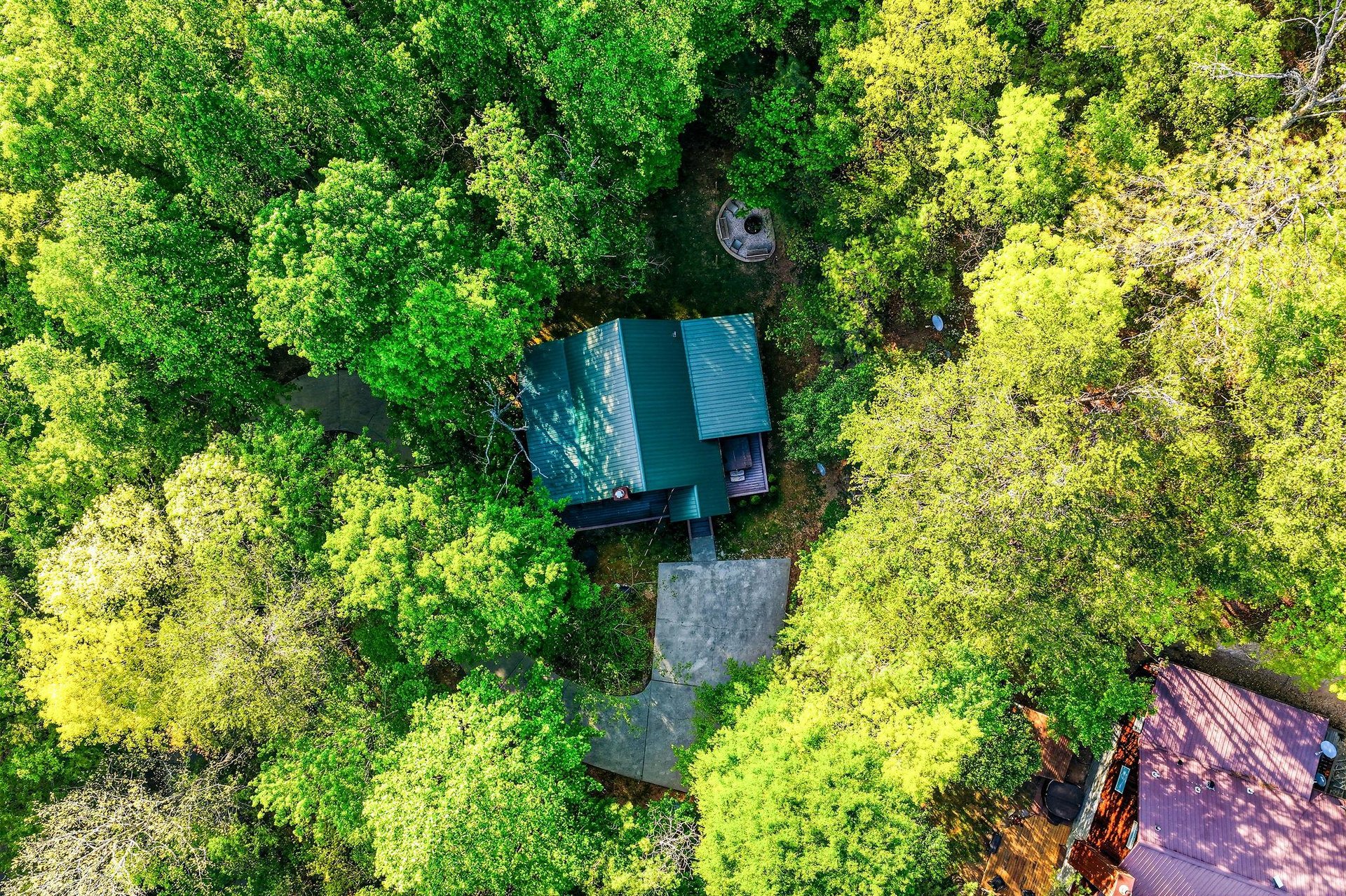 Aerial view reveals the property nestled within lush forest canopy, offering complete privacy and natural tranquility.