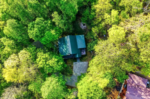 Aerial view reveals the property nestled within lush forest canopy, offering complete privacy and natural tranquility.