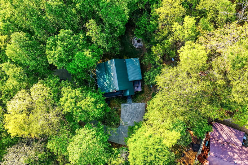 Aerial view reveals the property nestled within lush forest canopy, offering complete privacy and natural tranquility.