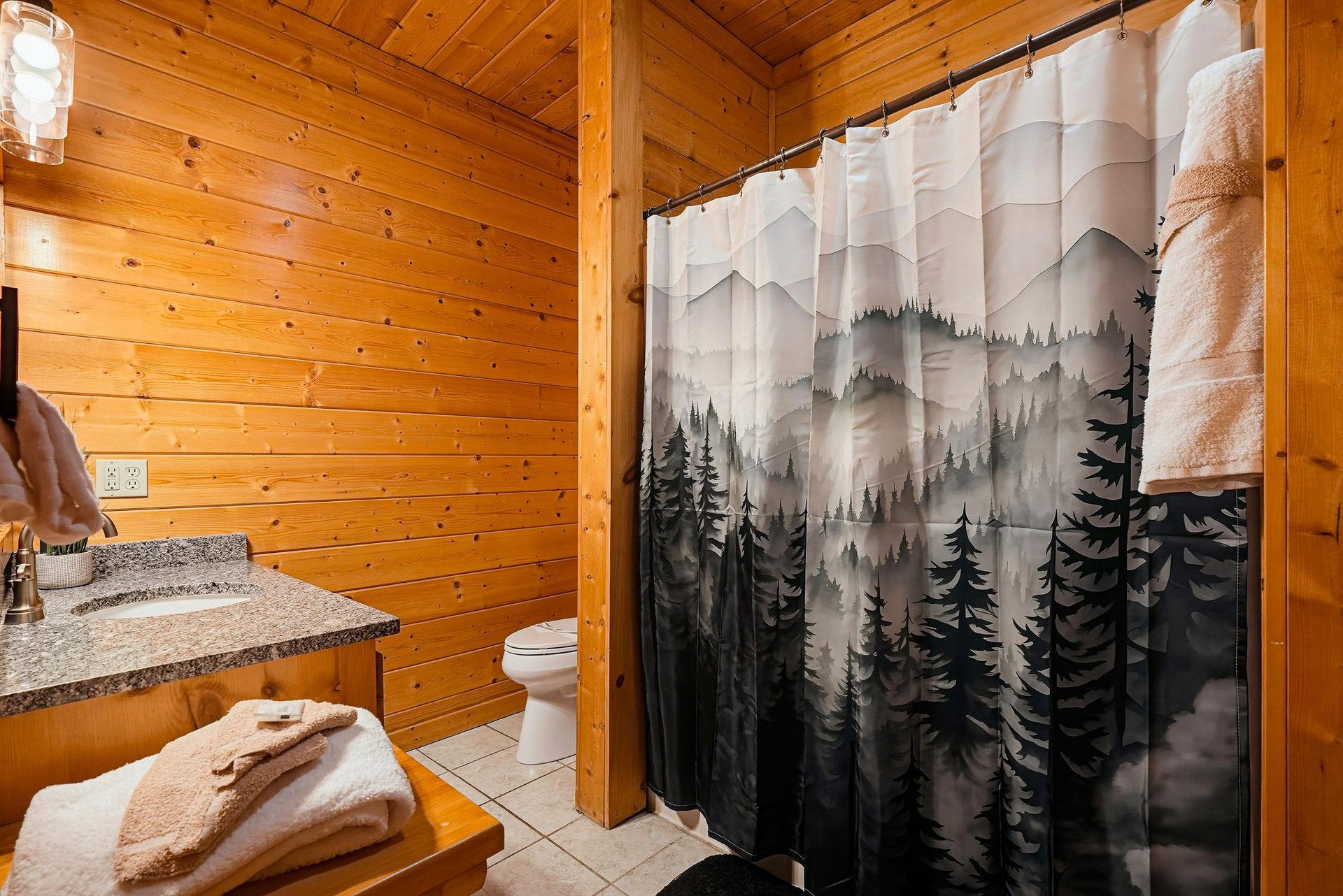 Cozy woodpaneled bathroom with natureinspired decor, ready for your refreshing cabin retreat.