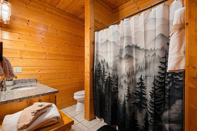 Cozy woodpaneled bathroom with natureinspired decor, ready for your refreshing cabin retreat.
