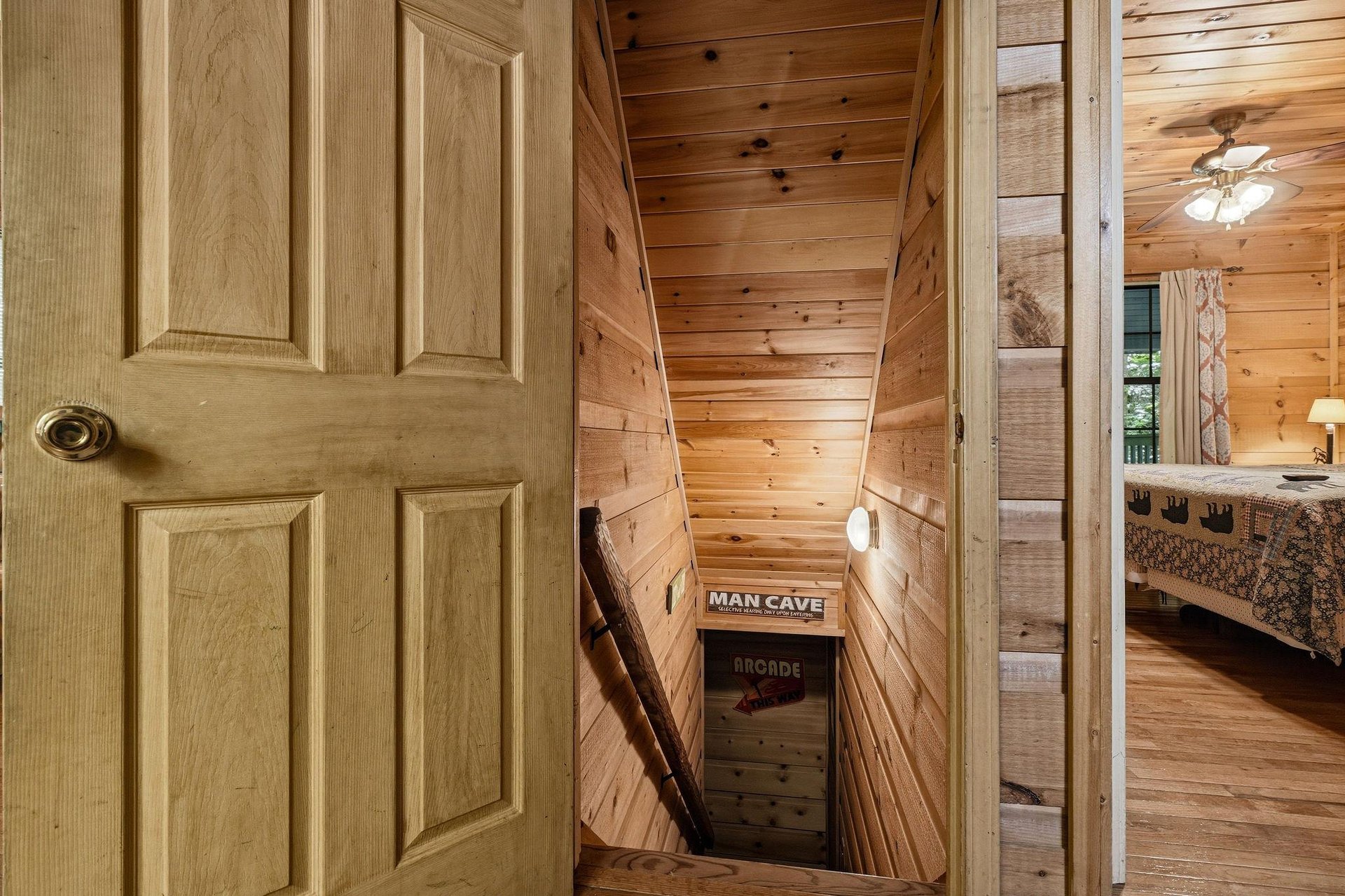 Charming wooden staircase leads down to a cozy retreat, with warm knotty pine walls inviting you to explore the unique spaces below.