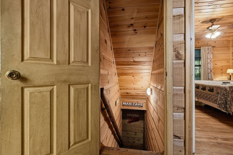 Charming wooden staircase leads down to a cozy retreat, with warm knotty pine walls inviting you to explore the unique spaces below.