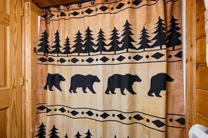 A rustic shower curtain with bear and pine tree silhouettes adds charming cabin character to your private bathroom.