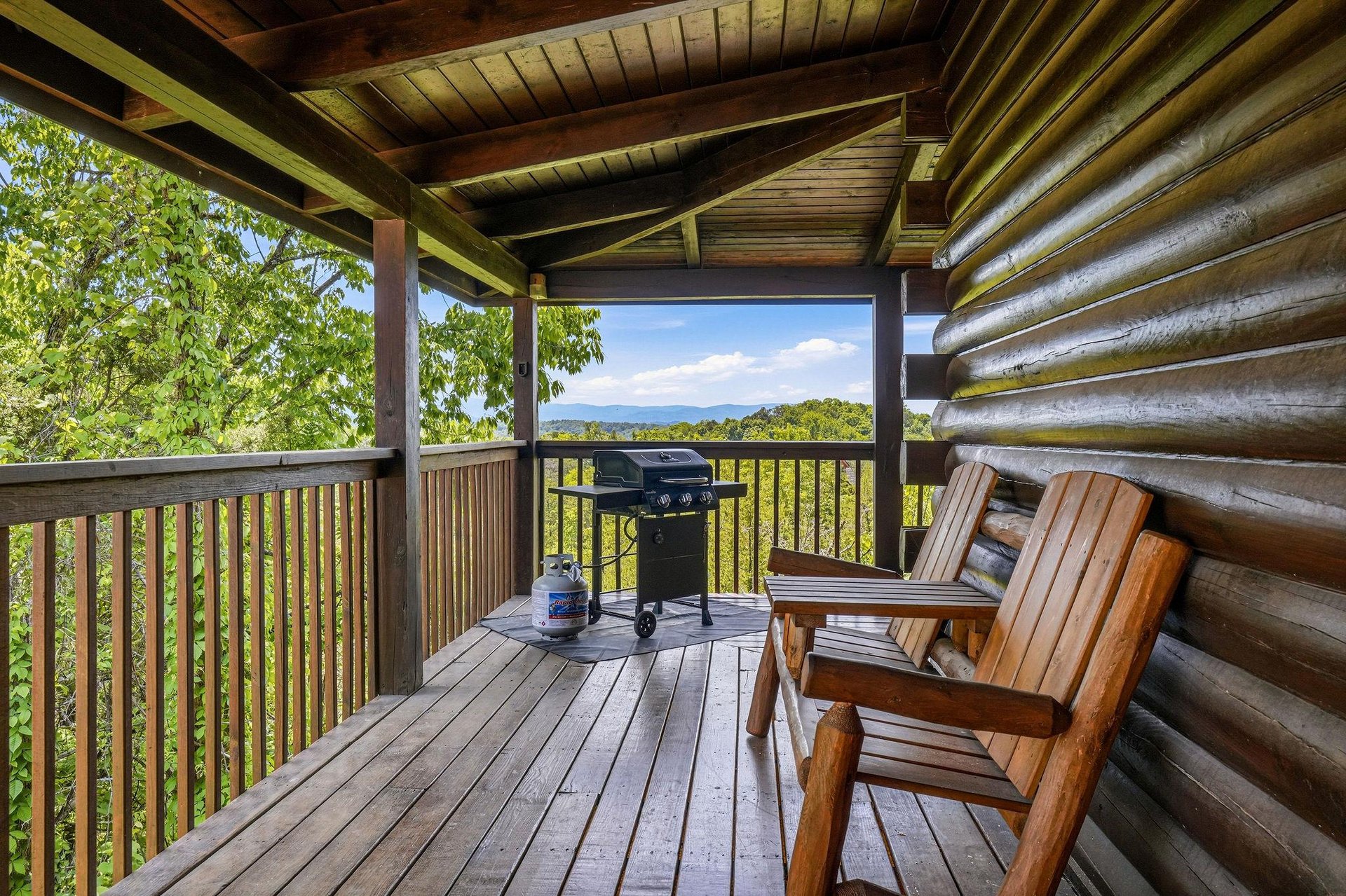 Relax on your private deck with sweeping mountain views, wooden seating, and a grill ready for outdoor meals. The covered porch invites peaceful mornings and serene evenings in nature.