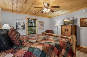 Settle into your cozy bedroom with its warm woodpaneled ceiling and handcrafted log bed, wrapped in a charming quilted bedspread that invites restful nights.