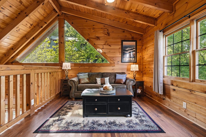 Cozy up in your rustic loft retreat with vaulted wood ceilings and peaceful forest views through oversized windows.