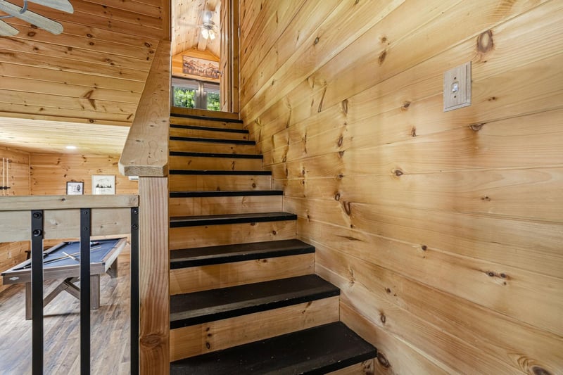 Warm wood surrounds you at every turn, from the honeytoned paneling to the sturdy staircase that beckons you upward. Natural light filters in, highlighting the rustic charm and inviting you to settle