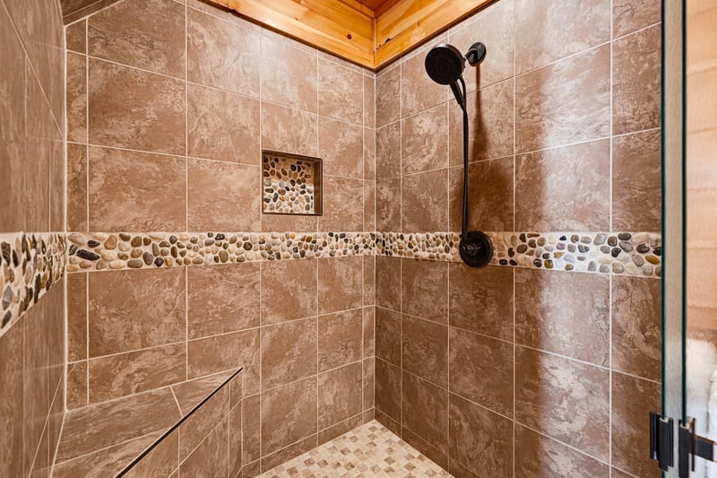 Step into your beautifully tiled walkin shower, where a soothing rainfall showerhead awaits and natural stone accents add a touch of rustic elegance to your daily routine.