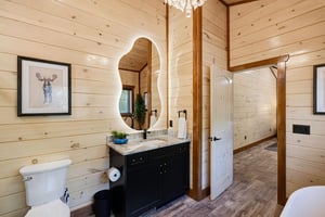 Your private bathroom combines rustic charm with modern comfort, featuring warm wood walls, a sleek black vanity, and thoughtful touches that make you feel right at home.
