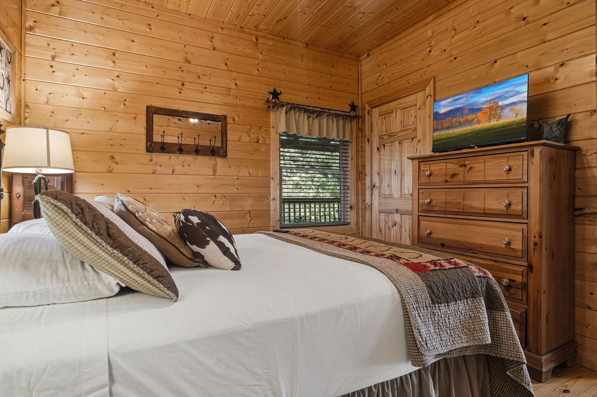 Sink into crisp linens in your cozy cabin bedroom, where warm wood walls and rustic charm create the perfect retreat after a day of adventure.