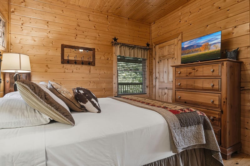 Sink into crisp linens in your cozy cabin bedroom, where warm wood walls and rustic charm create the perfect retreat after a day of adventure.
