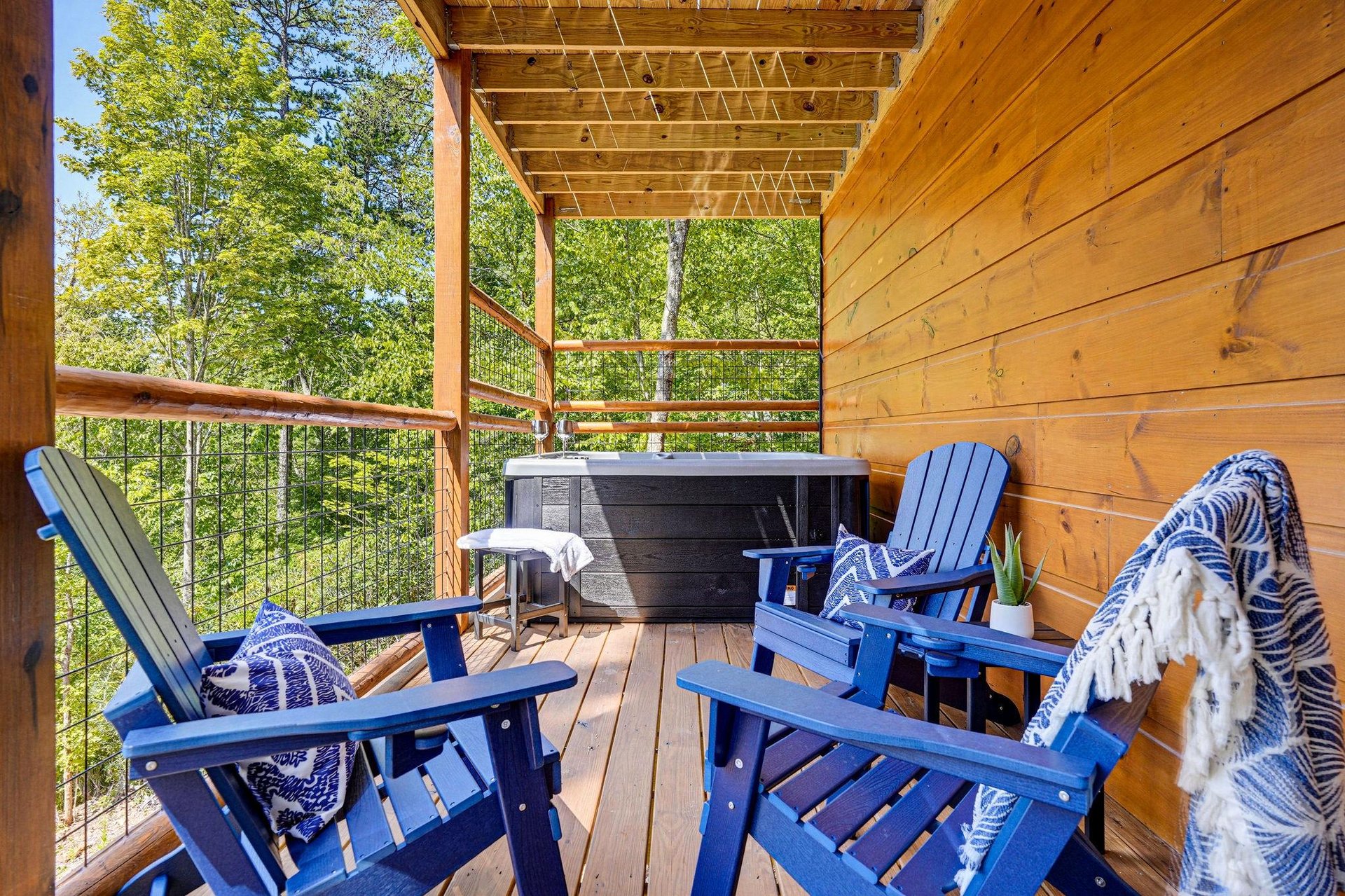 Your private covered deck surrounded by lush treetops, complete with a hot tub and cozy Adirondack chairs—perfect for soaking in natures calm after a day of adventure.