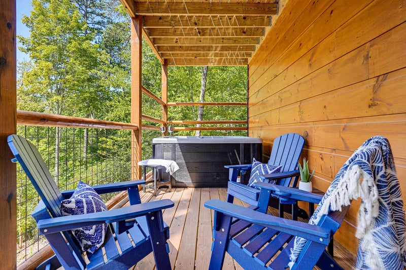 Your private covered deck surrounded by lush treetops, complete with a hot tub and cozy Adirondack chairs—perfect for soaking in natures calm after a day of adventure.