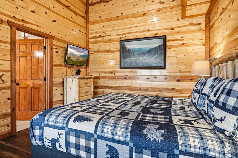 Drift off to sleep in your cozy log cabin bedroom, where rustic charm meets wilderness comfort beneath warm wood beams.