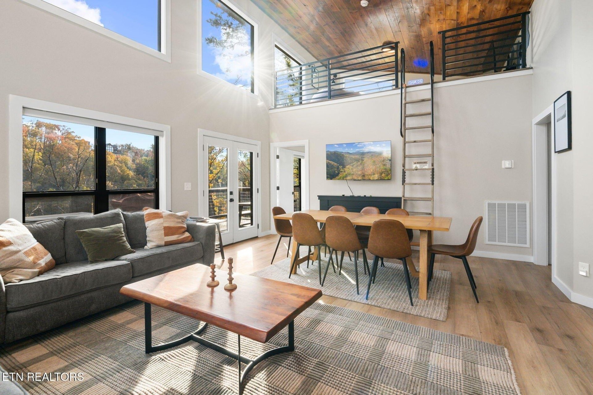 Sunlight pours through floortoceiling windows, framing views of autumn foliage while you gather around the handcrafted dining table or unwind on the plush sofa beneath soaring ceilings.
