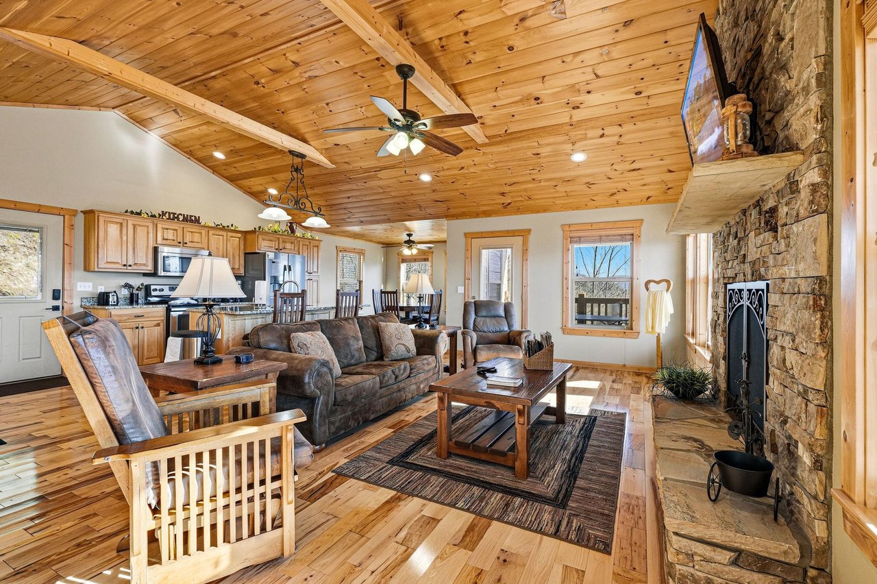 Relax in your rustic retreat where exposed wood beams meet cozy leather seating, while the stone fireplace and open kitchen create perfect gathering spaces.