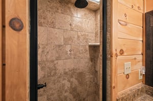 Rinse off under the warm, walkin shower framed by earthy tile, nestled into rustic wood paneling that echoes a cozy cabin vibe.