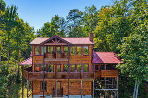 Spacious log cabin retreat nestled among towering trees, offering a private woodland escape with multiple levels of covered decks and rustic mountain charm.