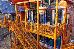 Rustic log cabin featuring expansive wooden balconies with handcrafted railings and mountain lodge charm.