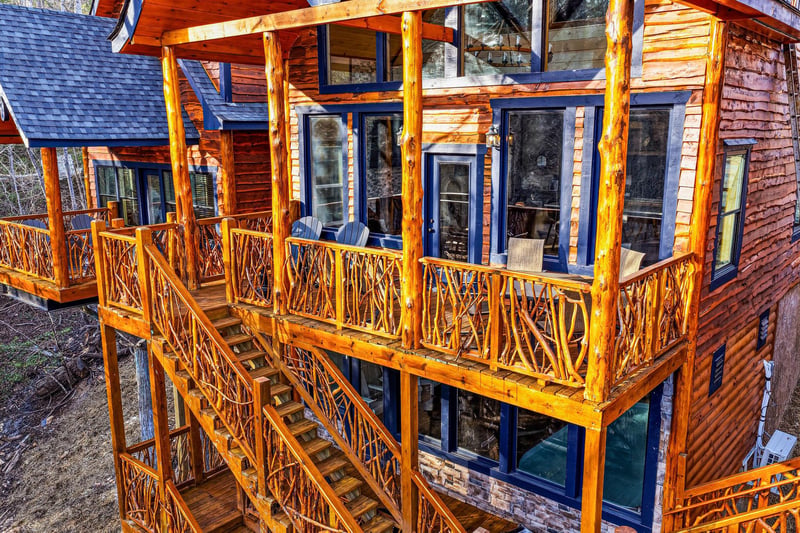 Rustic log cabin featuring expansive wooden balconies with handcrafted railings and mountain lodge charm.