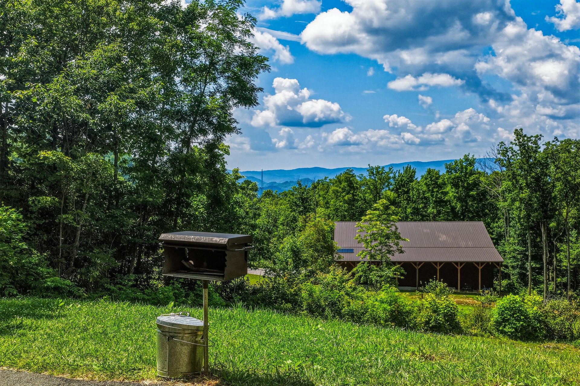 Secluded mountain retreat with BBQ grill and sweeping views of lush forest and distant peaks—ideal for peaceful getaways and outdoor dining.