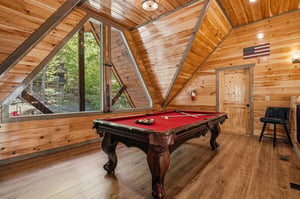 Challenge friends to pool in your rustic loft game room, featuring soaring wood beams and forest views through dramatic Aframe windows.