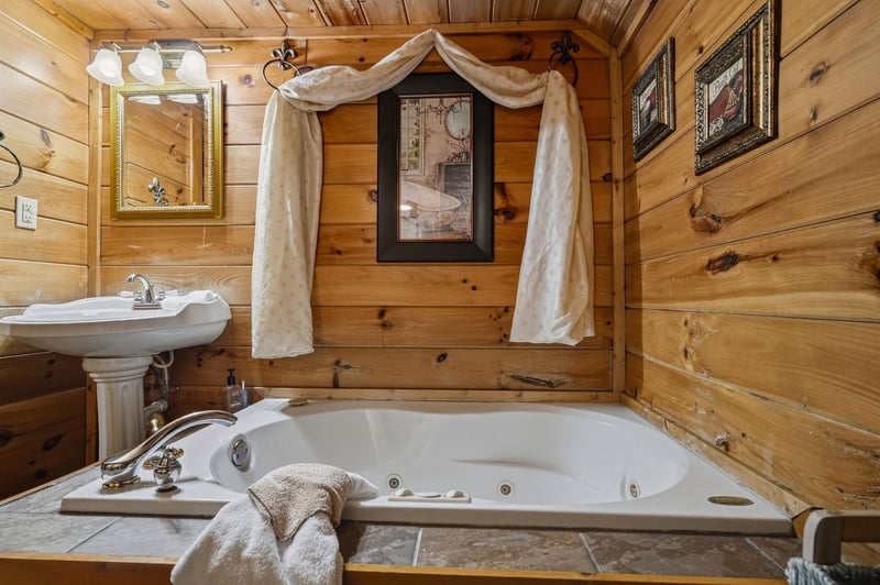 Sink into rustic charm in this cozy bathroom, where warm wood paneling meets a welcoming jetted tub—your perfect retreat after a day of mountain adventures.