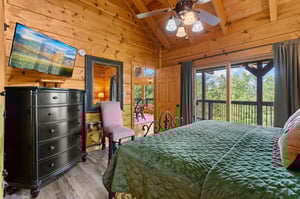 King bed facing chair with mirror and dresser with tv