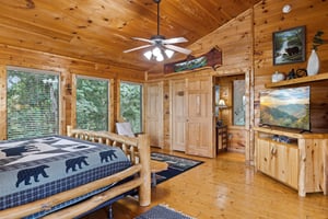 King bed with tv and several windows