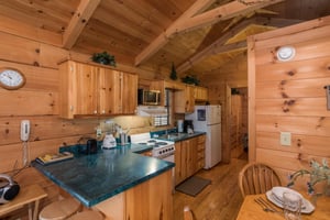 Looking into the kitchen with white appliances from the dining space at Boogie Bear, a 1bedroom cabin rental located in Gatlinburg