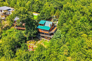 A charming cabin retreat nestled in a lush, treecovered mountainside offers peaceful seclusion and natural beauty, complete with outdoor seating areas and multiple decks for relaxation.