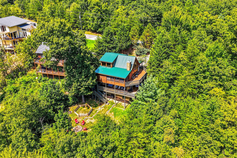 A charming cabin retreat nestled in a lush, treecovered mountainside offers peaceful seclusion and natural beauty, complete with outdoor seating areas and multiple decks for relaxation.