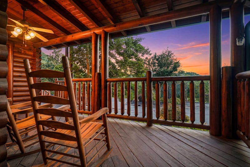A stunning mountain sunset paints the sky while you unwind in your rocking chair on the peaceful covered balcony, surrounded by lush trees and serene views.