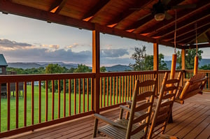 Gentle evening light washes over your private covered deck, where wooden rockers invite quiet moments gazing at layered mountain ridges and lush greenery stretching to the horizon.